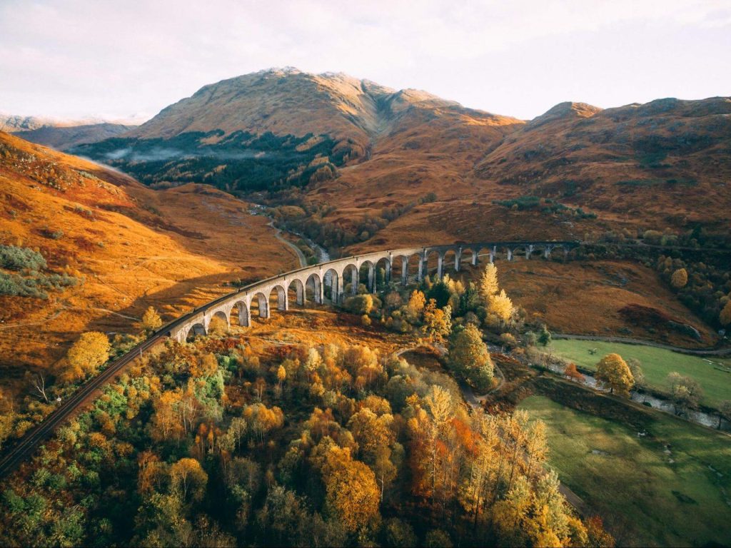 A white bridge straddles a river, surrounded by orange and green mountains in Fort William, Scotland. Photo: Connor Mollison