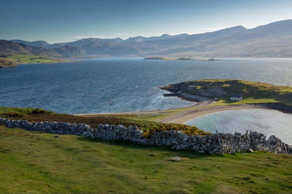 A view of distant mountains and blue sea from a bay in Scotland. Photo: Piotr Musioł